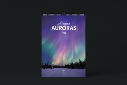 The 2027 Awesome Auroras wall calendar, its cover a photo of purple, pink and green aurora rays over spruce trees and a snowy road, shown against a dark background.